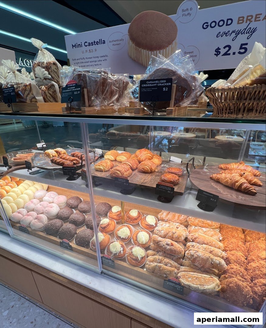 A display case filled with various freshly baked pastries and breads at Paris Baguette.