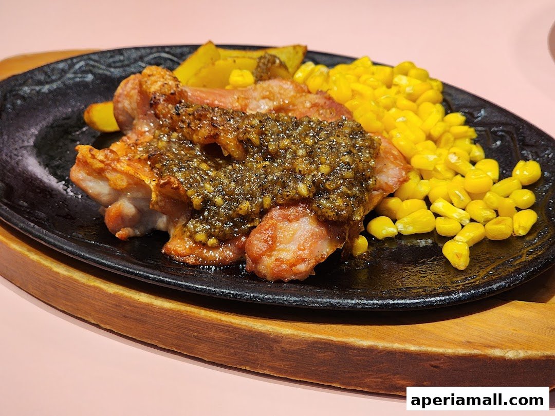 A sizzling hot plate of chicken with corn and potatoes, topped with a savory sauce.