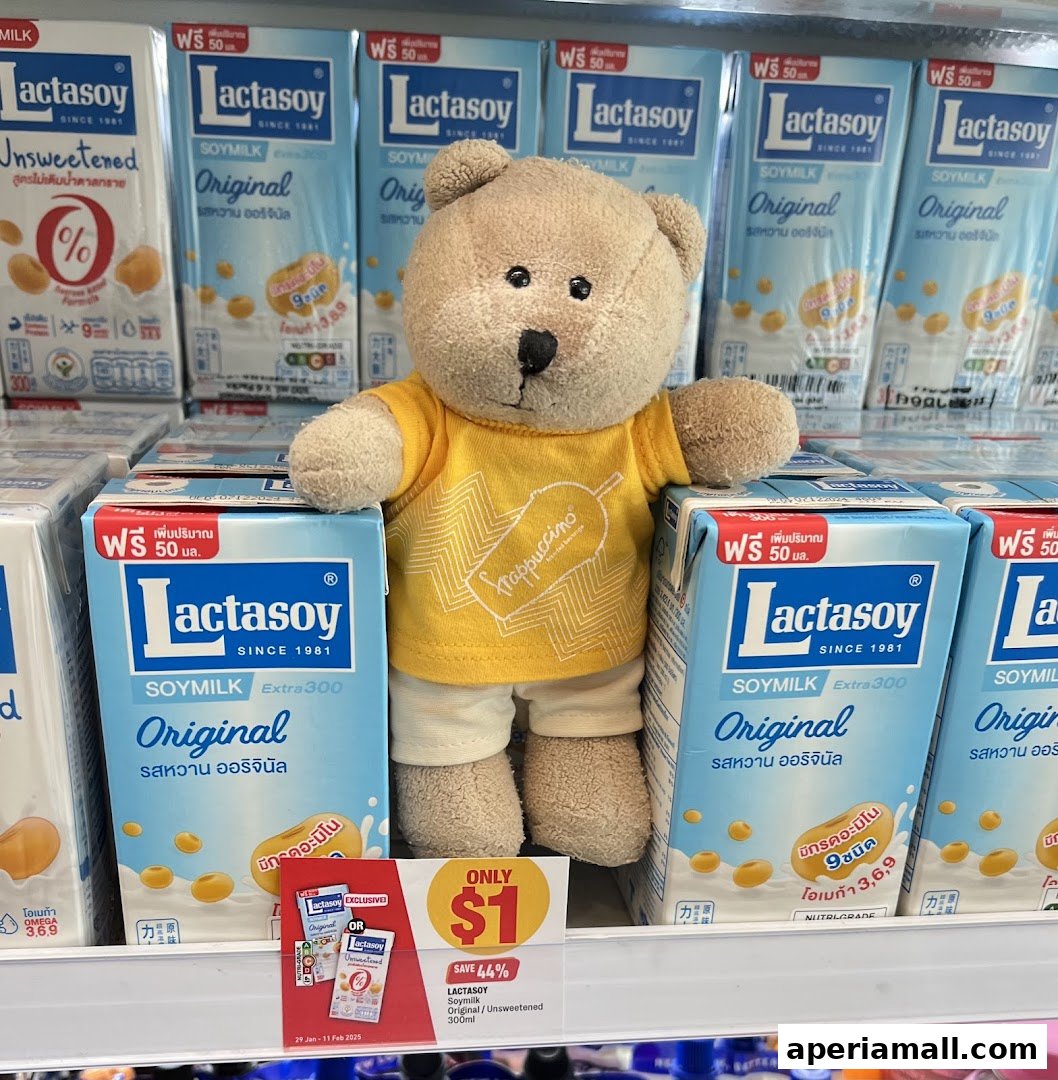 A teddy bear wearing a yellow shirt stands in front of shelves stocked with Lactasoy soymilk cartons.