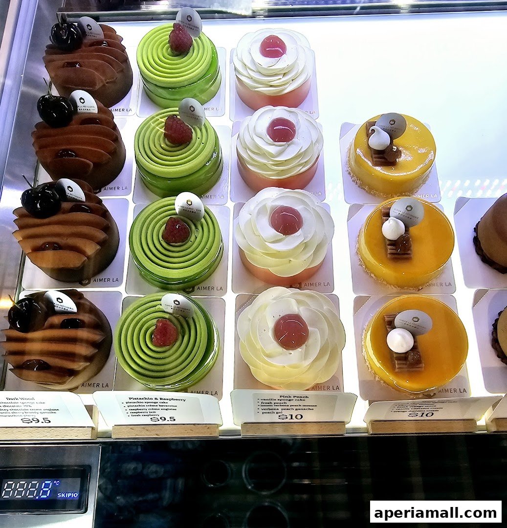 A display case filled with beautifully decorated pastries and cakes from Aimer La Patisserie.