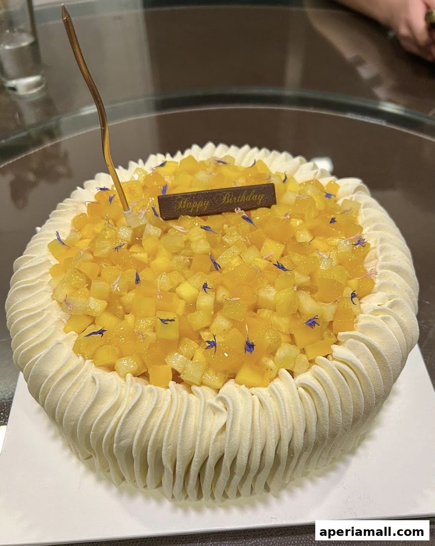 A beautifully decorated birthday cake topped with diced mango and edible flowers.