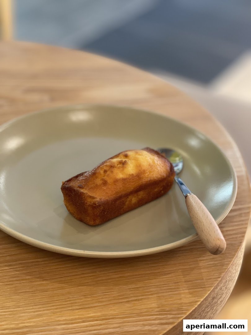 A golden-brown mini loaf cake served on a light green plate with a spoon.