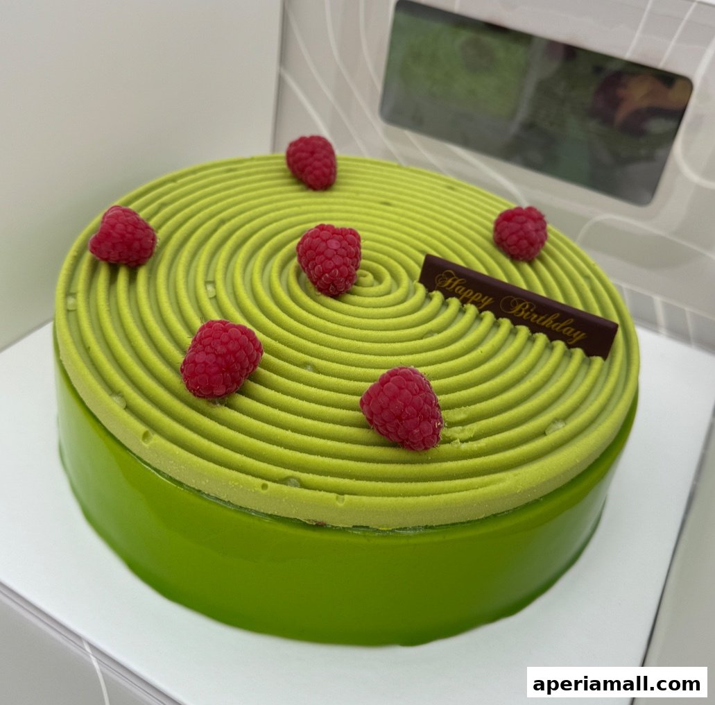 A vibrant green cake with a spiral pattern and fresh raspberries, topped with a 'Happy Birthday' chocolate plaque.