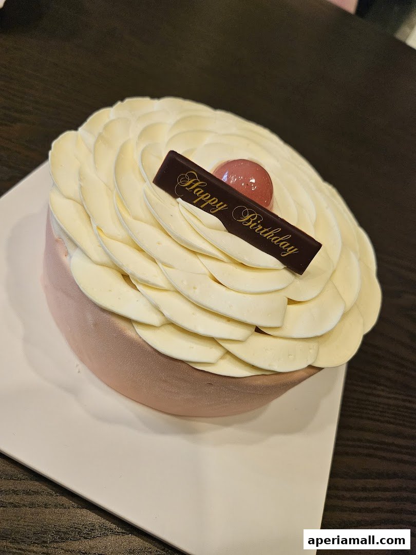 A beautifully decorated cake with white frosting and a 'Happy Birthday' chocolate plaque.