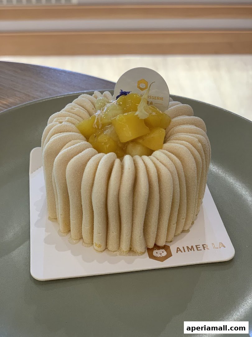 A beautifully decorated cake with mango topping on a plate from Aimer La Patisserie.