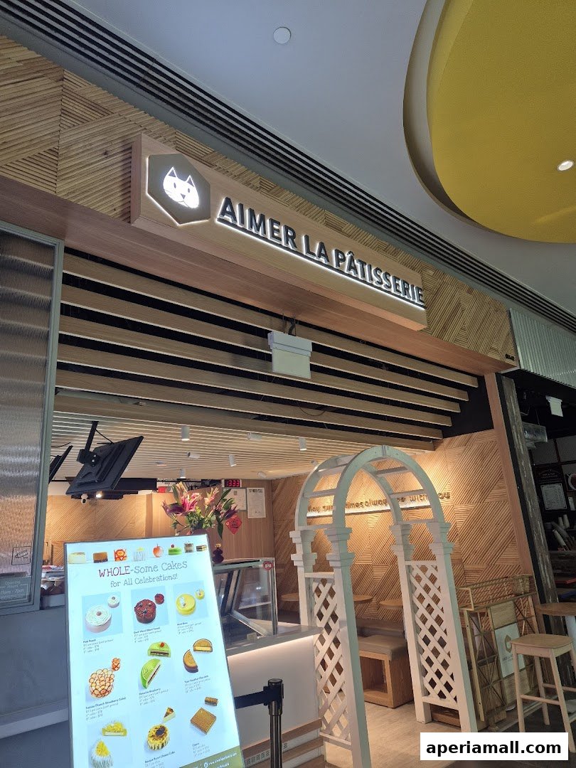 The entrance of Aimer La Patisserie, a cake shop, with a menu display and decorative arch.