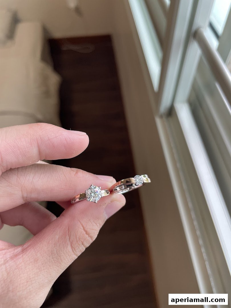 A hand holds two diamond rings, showcasing their intricate designs and sparkling stones.