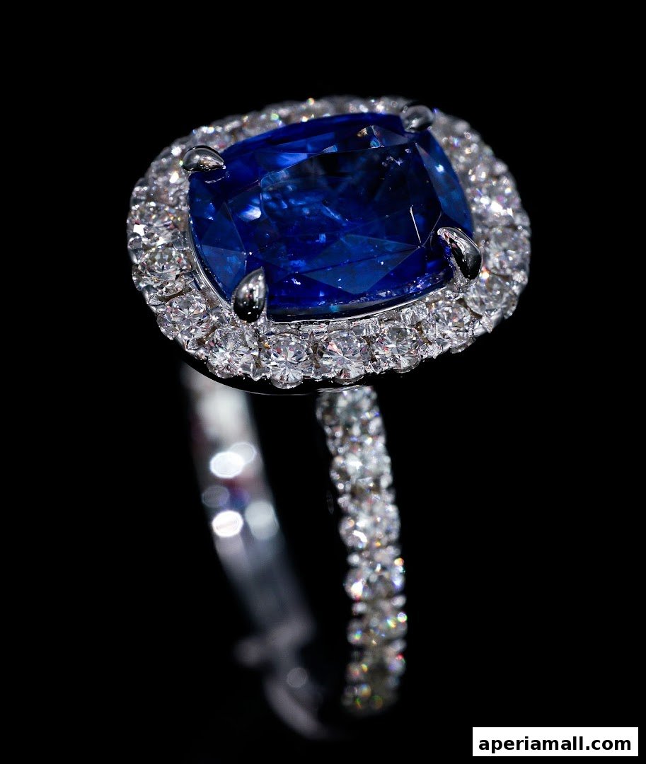 A close-up of a stunning sapphire and diamond engagement ring on a black background.
