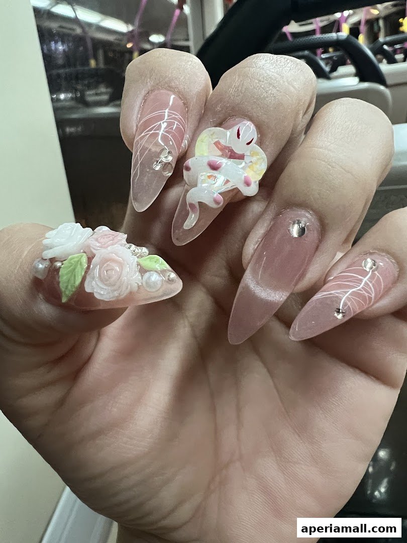 Close-up of a hand with elaborately decorated nails featuring 3D floral designs and a snake.