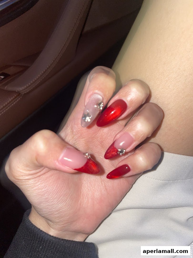 Close-up of hands with beautifully decorated red and clear stiletto nails with rhinestones.