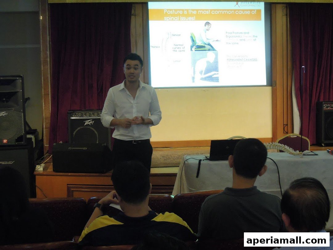 A chiropractor presents a seminar on posture and spinal health to an audience.