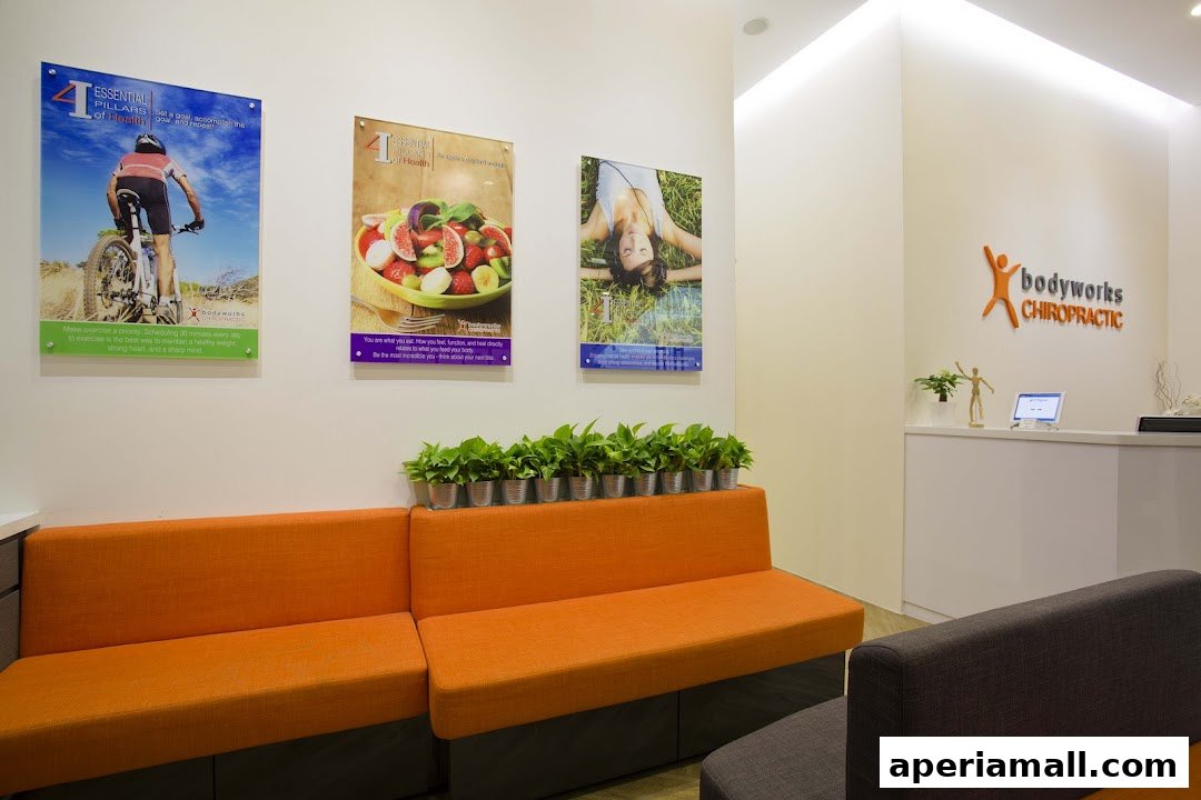 A waiting area with orange couches, plants, and posters at Bodyworks Chiropractic.