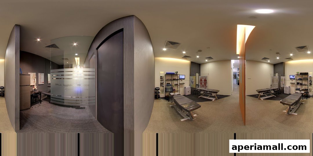 Interior view of a modern chiropractic clinic with treatment tables and anatomical charts.