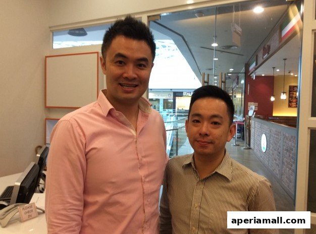 Two men smiling at the camera in what appears to be a clinic or reception area.