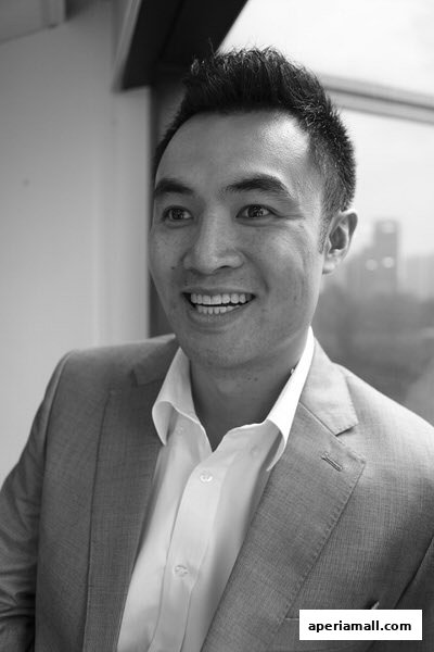 A black and white portrait of a smiling man in a suit and shirt.