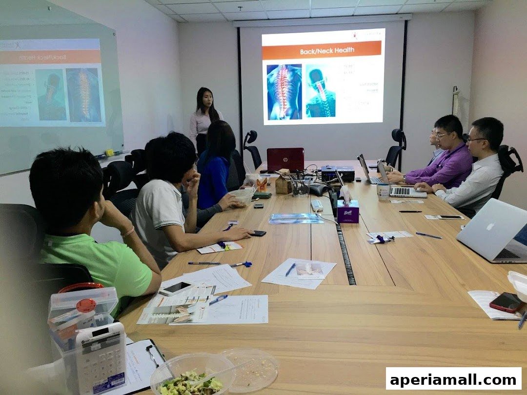 A group of people attend a presentation on back and neck health in a modern office setting.