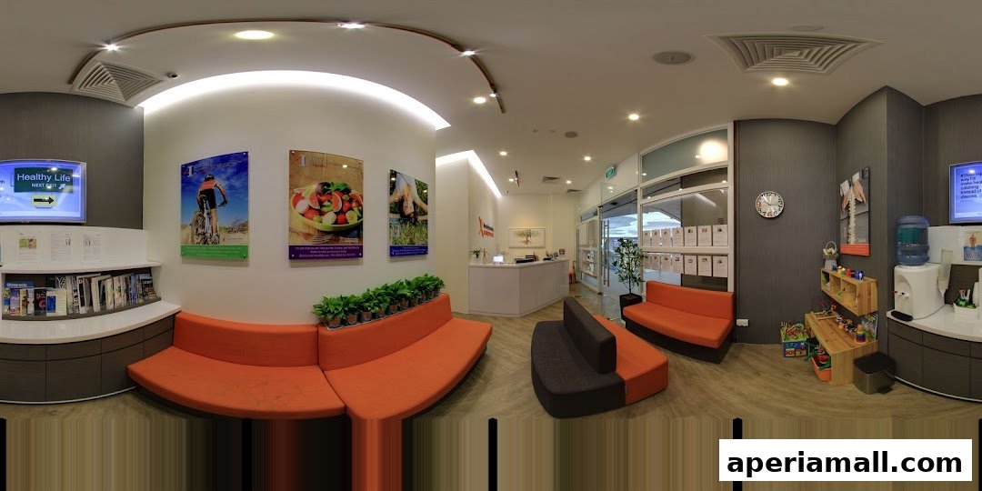 The interior of a chiropractic clinic with a reception desk, seating areas, and health-related posters.