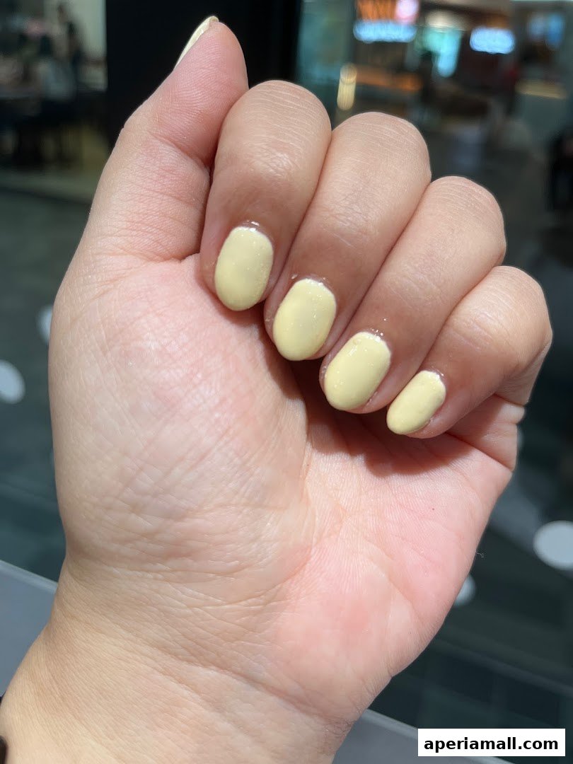 A close-up of a hand with freshly painted light yellow nails.