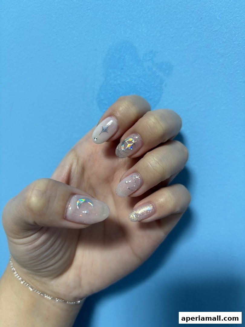 A hand with beautifully decorated nails featuring stars, moons, and glitter.