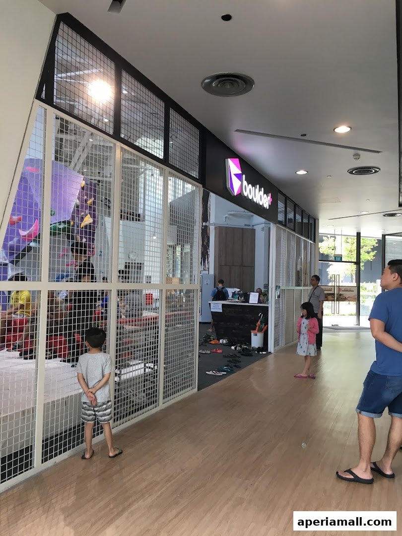A view of the Boulder Aperia climbing gym entrance with people inside and outside.