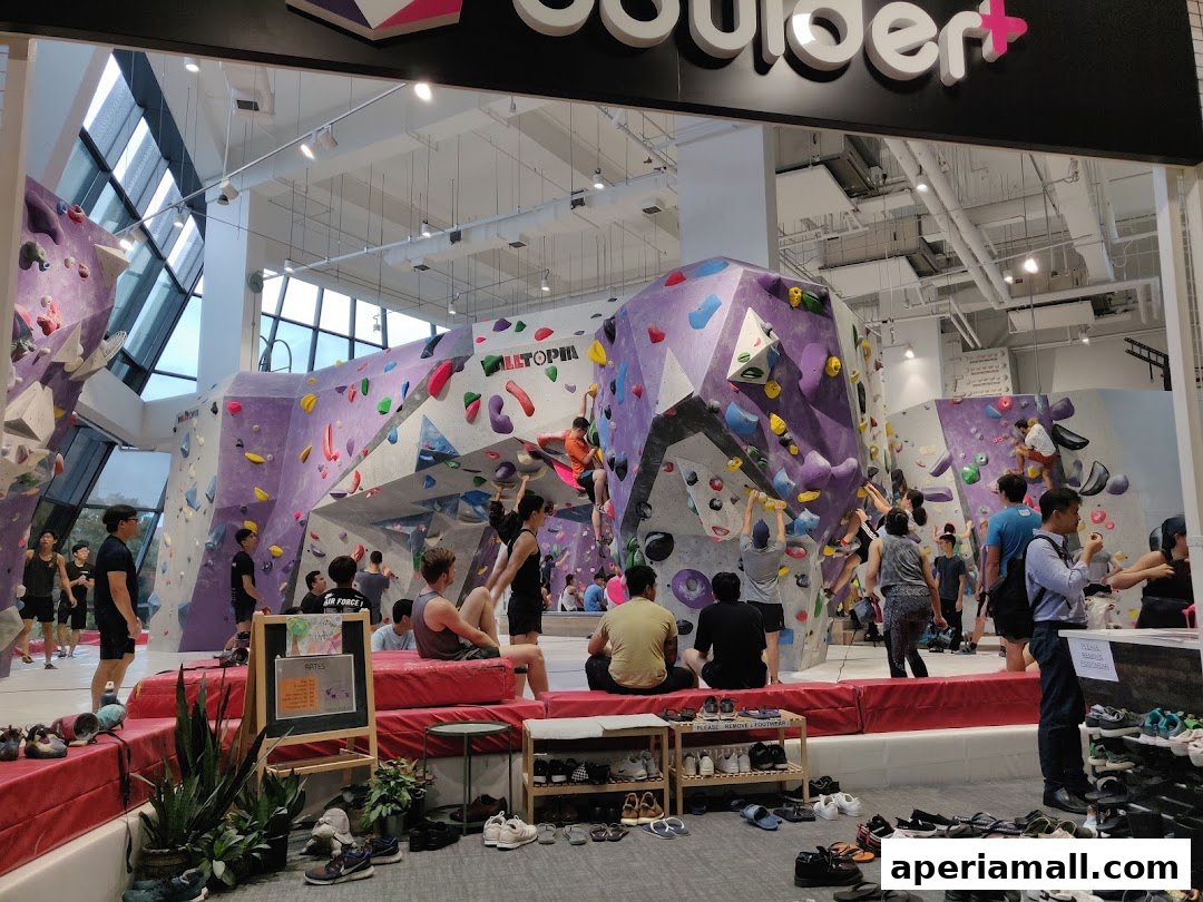 People climbing on colorful bouldering walls inside a modern gym.