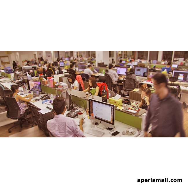 An open-plan office with many employees working at their desks.