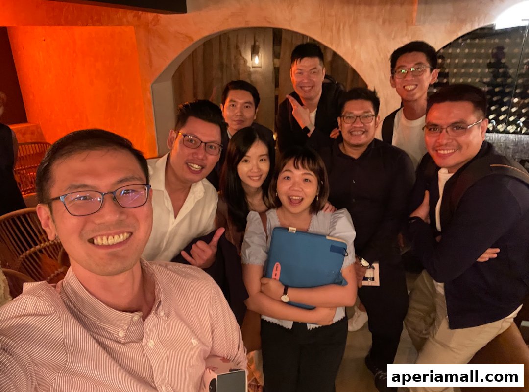 A group of smiling people posing for a selfie in a dimly lit, stylish venue.