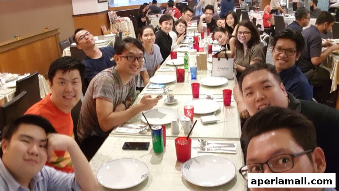 A group of people are seated at a long table, enjoying a meal together.