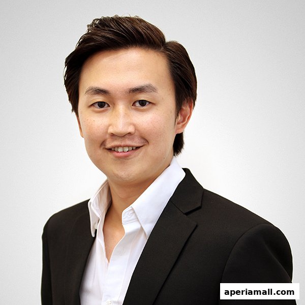 A headshot of a smiling young man in a black suit and white shirt.