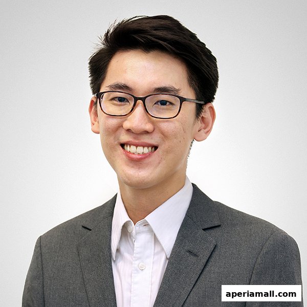 A headshot of a smiling young Asian man wearing glasses and a suit.