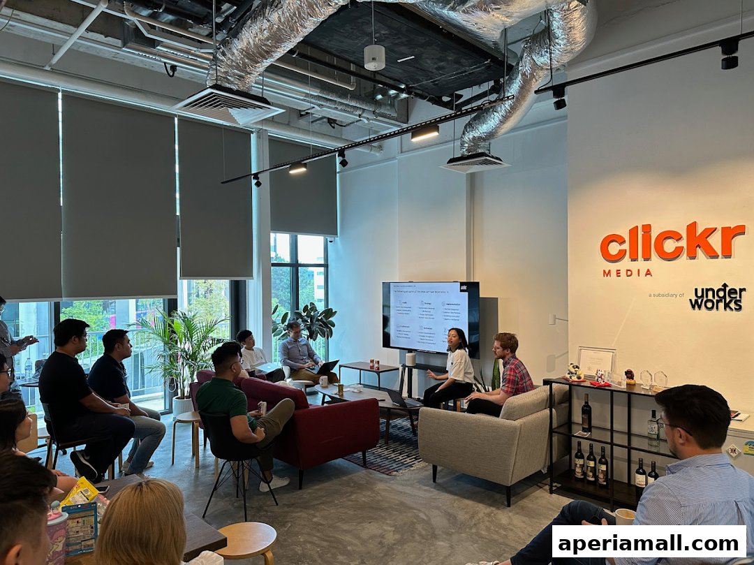 A team meeting is taking place in a modern office with a presentation on a large screen.