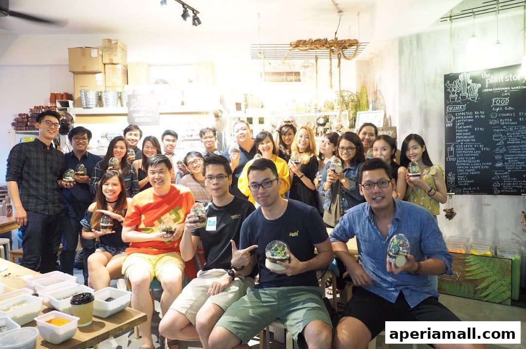 A group of people posing for a photo inside a shop, holding small terrariums.