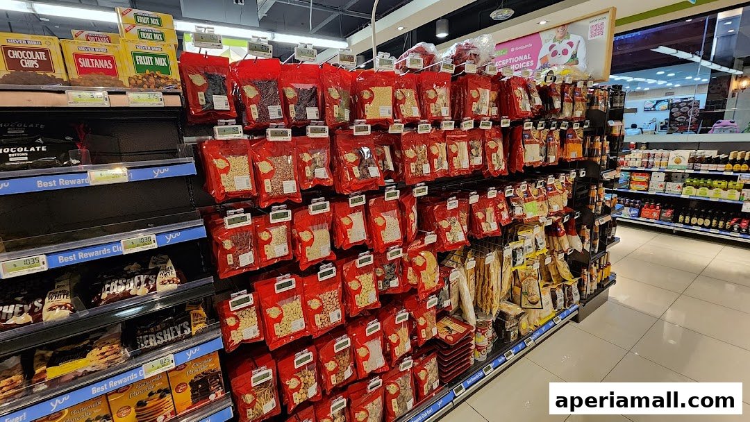 Aisle of a supermarket with shelves stocked with various food items, including nuts, dried fruits, and chocolates.