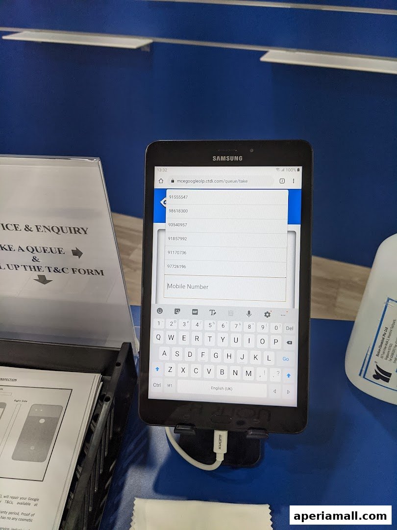 A tablet displaying a queue management system with a keyboard and a sign for service and enquiry.