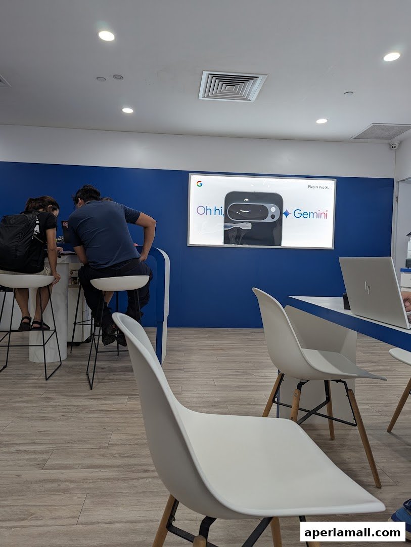 People are seated at a counter in a modern retail store with a large screen displaying Google products.