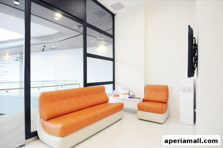 A modern waiting area with orange seating, a water cooler, and a TV mounted on the wall.