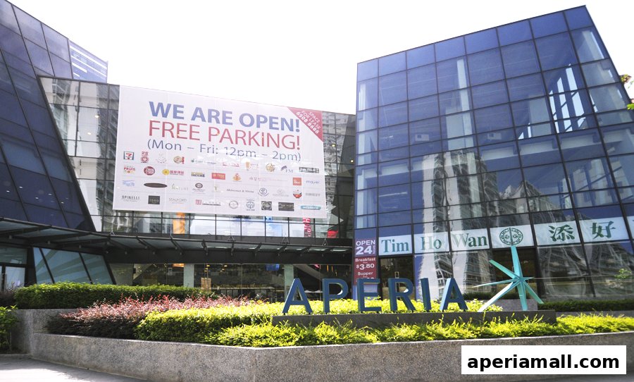 Exterior of a modern building with a large banner advertising free parking and various shop logos.