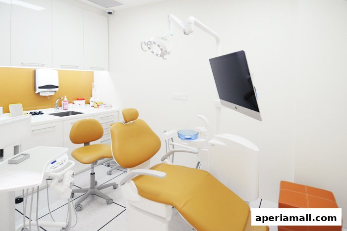 A modern dental examination room with orange chairs and a computer monitor.