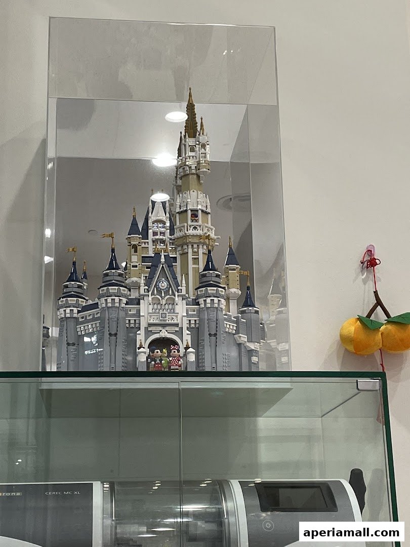 A detailed Lego replica of a Disney castle displayed in a glass case.