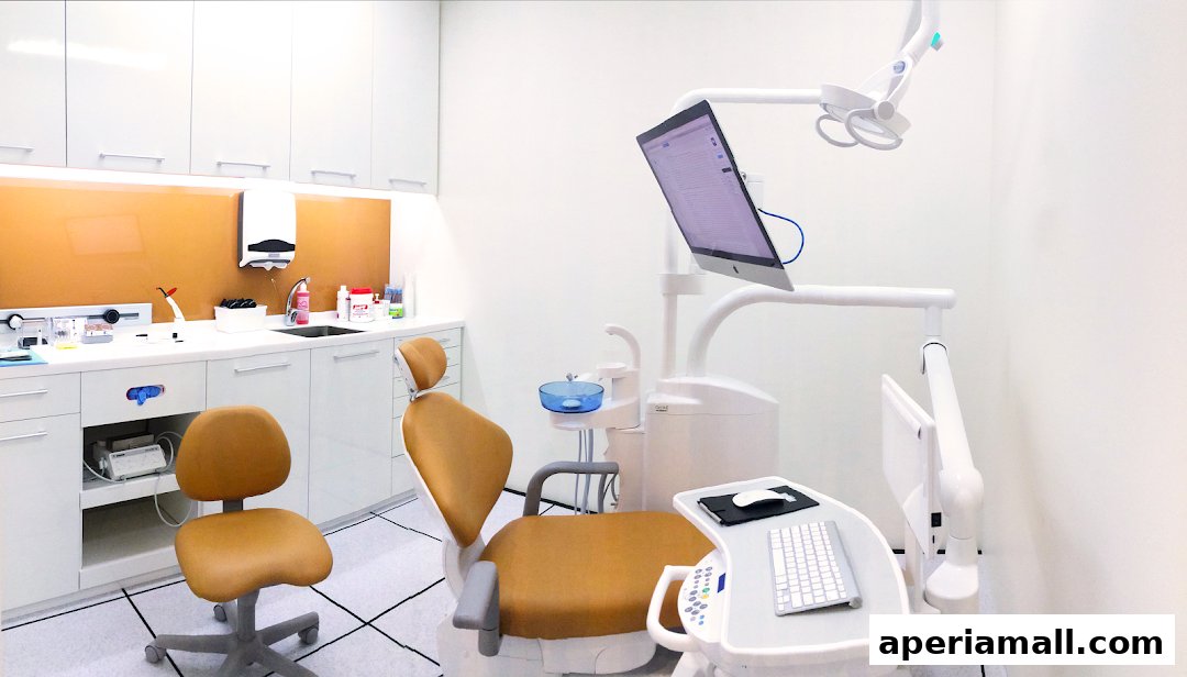 A clean and modern dental examination room with a dental chair, equipment, and computer.
