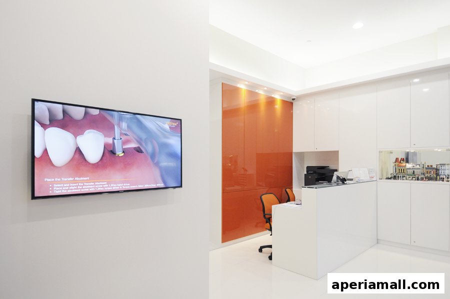 A modern dental clinic reception area with a TV displaying a dental procedure.