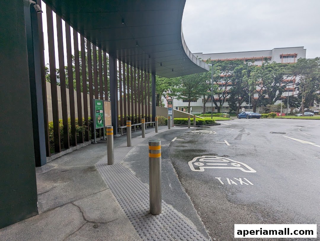 A taxi stand with a covered waiting area and taxi markings on the wet road.