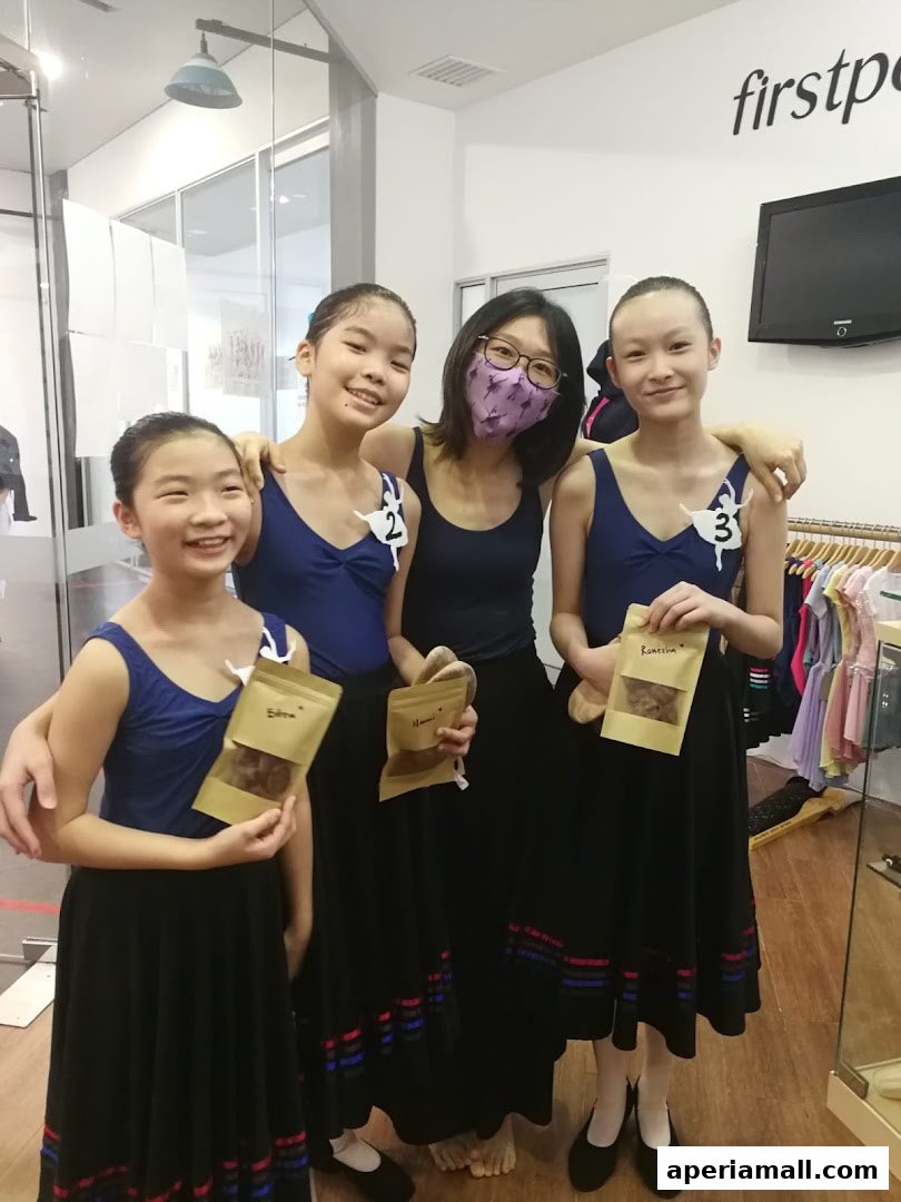 A dance instructor and three students pose together, holding small bags of treats.
