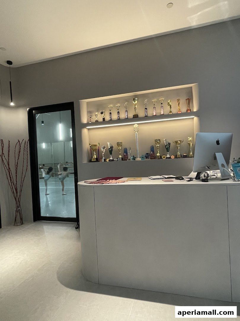 Reception area of a dance school with trophies displayed and dancers practicing in the background.