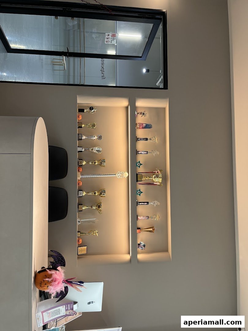 A reception desk with trophies displayed on shelves, and a view into a dance studio.