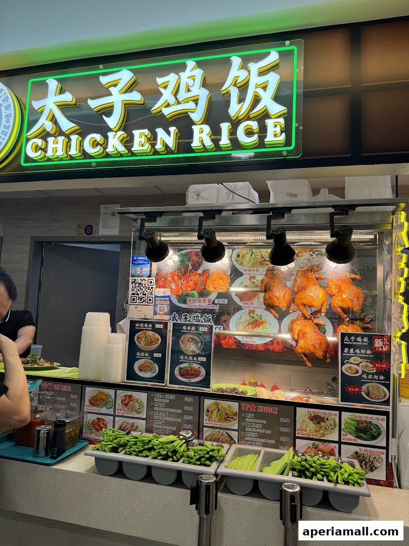 A food stall displaying roasted chickens and various noodle and rice dishes.