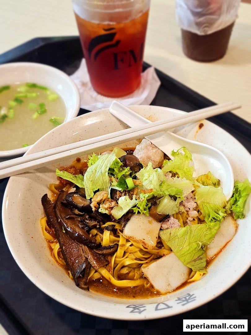 A bowl of noodles with mushrooms, meat, and lettuce, served with soup and iced tea.