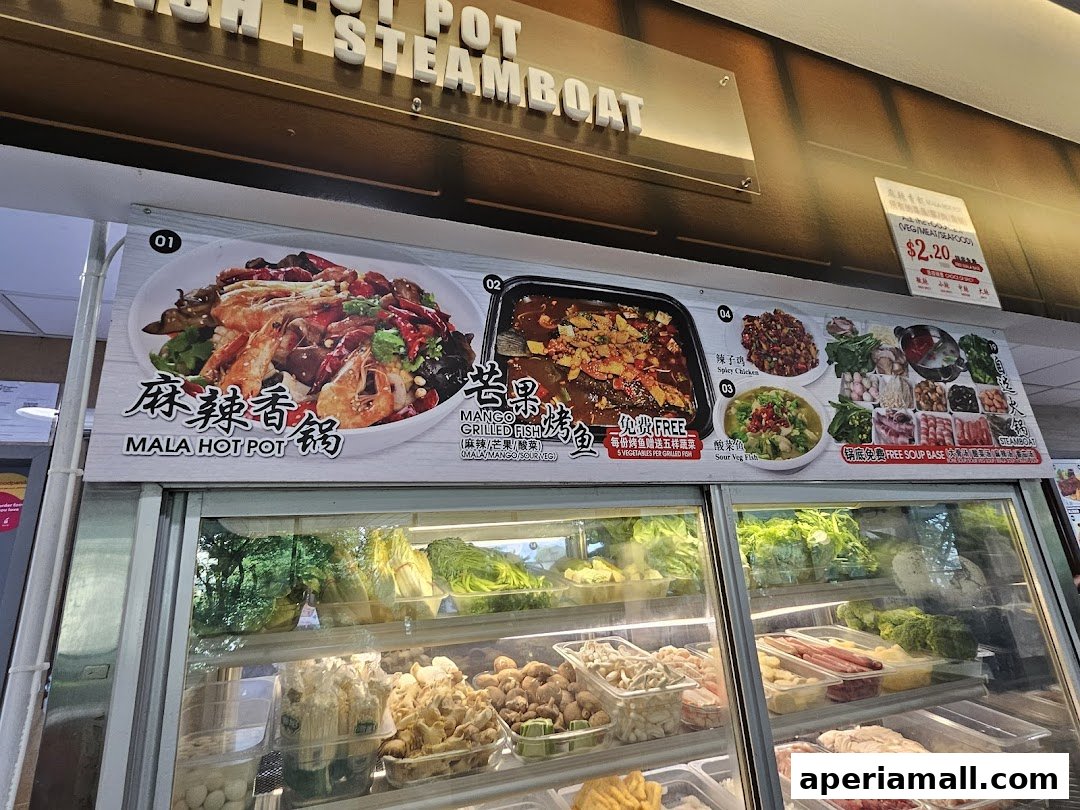 A food stall display featuring Mala Hot Pot, grilled fish, and various fresh ingredients for steamboat.