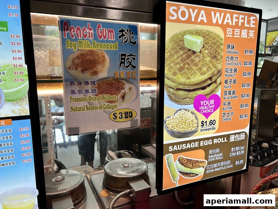 A menu board displaying Soya Waffles, Peach Gum Soy Milk Beancurd, and Sausage Egg Rolls.