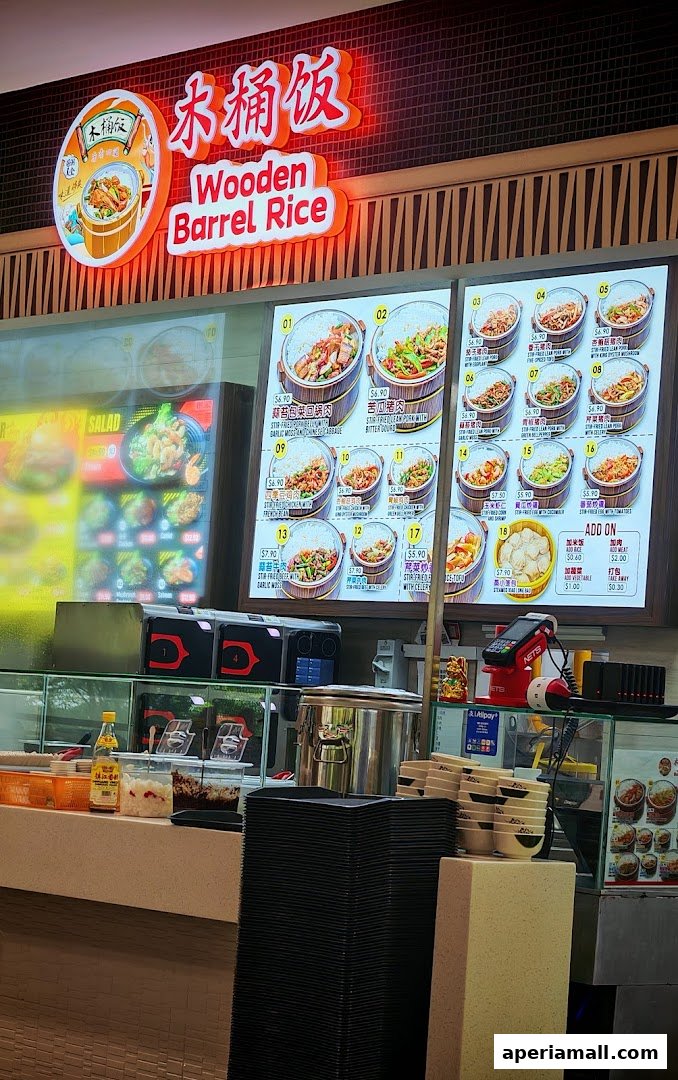 A brightly lit menu board displays various rice dishes in wooden barrels at FM FoodMaster.